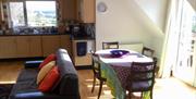 A dining room table in an open plan living space and kitchen.