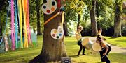 Image shows a tree with paint pallets and 3 men beating drums