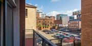 An inner-city view from a balcony and a car park.