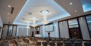 A seated presentation hall with a stage, podium and projector screen.