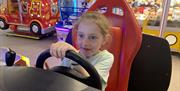 Girl enjoying a steering wheel racing arcade game.