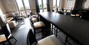 Tiled dining area with tables and chairs, a TV and patio doors leading to an outside sitting area.