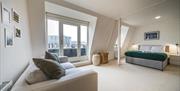 A large double bedroom with a grey sofa and a glass balcony door.