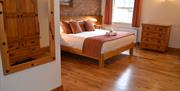 This spacious accessible room features a comfortable double bed, wooden furniture, including a mirror, drawers, and bedside lamps, and a fully accessi