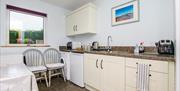 Image shows kitchen area with table and 2 wooden chairs