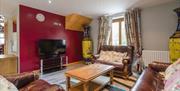 Image shows lounge area with leather sofa and 2 armchairs, coffee table, rug and TV