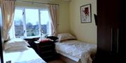 A twin bedroom with two single beds and a large window.