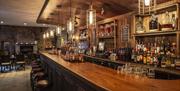 Image shows long view of the bar with various spirits  lined up behind the bar