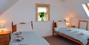 Image shows twin bedroom with small window between beds