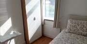A photo of a bedroom with a double bed, window, cupboard and foldable table.