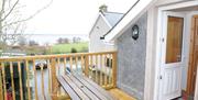 A decked entrance to a second story loft cottage with a picnic table and a view of a lake.