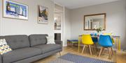 A dining/sitting room with a dining table, sofa and a doorway leading to a kitchen.