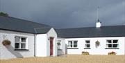 Image shows front of white washed cottages showing one with a red door