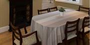 A dining room with a table for six and a fireplace.