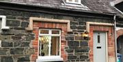 Image shows front door and window of the cottage