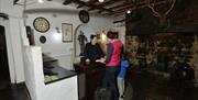 A woman and little boy checking in in a stone reception area with a fireplace and a deer trophy.