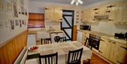 A fully fitted kitchen with a dining table and traditional wooden cupboards.