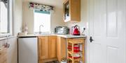 Small kitchen area inside Seal Cabin with sink, undercounter fridge and storage for pots/pans with kettle and microwave.