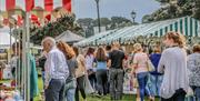 crowds of people browsing busy seaside market stalls