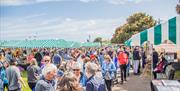 crowds of people browsing busy seaside market stalls