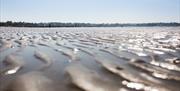 Close up photo of the ripples of sand on Ballyholme Beach with the promenade and bathers in backdrop