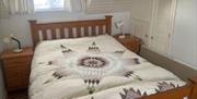 A view of one of the upstairs bedrooms. A dormer window is above the bed.