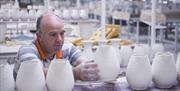 male pottery worker placing pottery onto shelf