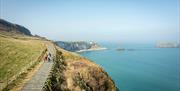 Group walks down path towards carrick-a-rede rope bridge