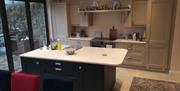 Image is of kitchen and dining area with an island, patio doors out on to courtyard