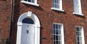 Image shows outside of property which is built in Georgian style with a white front door and sash windows. There are 2 small steps up to front door.