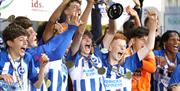 a male youth football team celebrates winning a trophy at Supercup NI