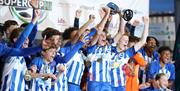 a male youth football team celebrates winning a trophy