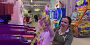 Girl collecting tickets with her mother from Skee-Ball machine in an arcade area