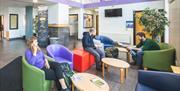 A photo of a communal lobby area with a group of people sitting together.