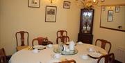 A dining room with a table set for six with two extra chairs and a large mirror