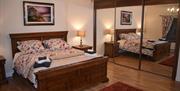 Wooden double bed with an image of Mussenden temple above and mirrored wardrobe to the side