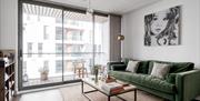 A living room with a green sofa, coffee table with books and a balcony.