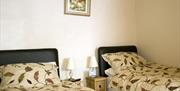 Image shows twin beds each with beside table and lamp