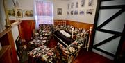 A small living room with floral chairs, a sofa, fireplace and titanic era photos on the walls.