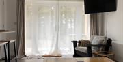 Patio doors, TV, coffee table and chair in the living area  at The Heagry
