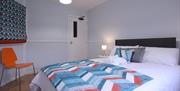 Double bedroom with white linen and orange and blue colour scheme