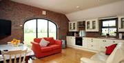 Image shows kitchen dining area with table, chairs,2 sofas and table with chairs