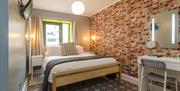 A double bedroom with a makeup desk, TV and red brick wallpaper.