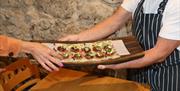 a chef holds a tray of salmon-based canapes while a person's hand reaches to lift one