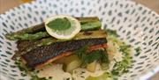 a salmon dish incorporated asparagrus and pickles, garnished with a slice of lemon
