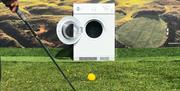 a person swings a golf ball in to an open washing machine