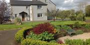 The rear of a house with a path and a garden area with a bench.