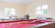 A games room with pool, table tennis, air hockey, table football and a barbecue.