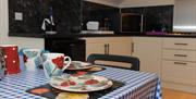 A kitchen dining area with a set table and a microwave, sink and washing machine.