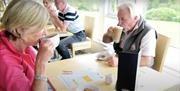 Two people having hot drinks in Cairndhu Golf Course Club House whilst reviewing menu